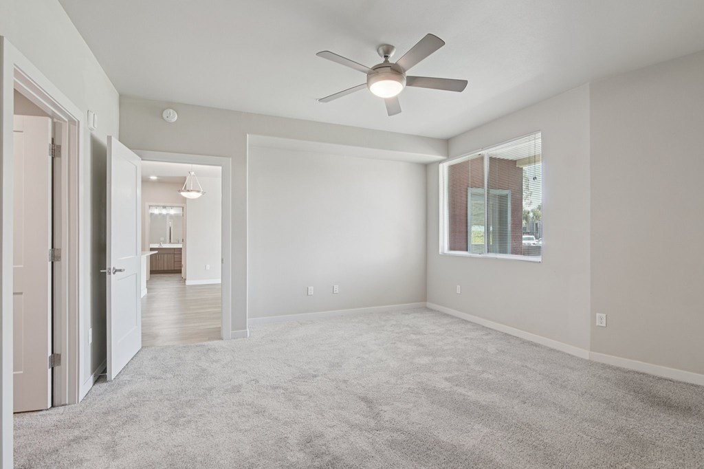 A spacious room with a ceiling fan and carpeted floor.