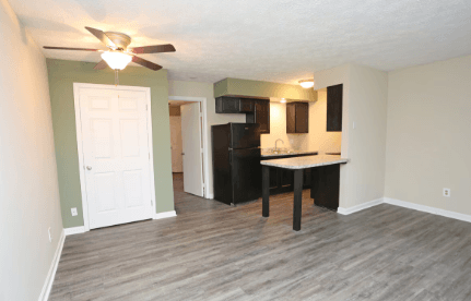 A room with a ceiling fan and a table with chairs.