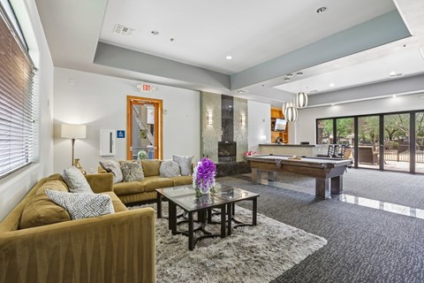 A living room with a brown couch and a pool table.