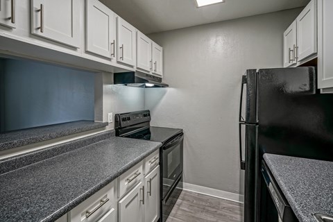 A black refrigerator sits next to a stove in a kitchen.