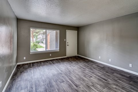 A room with a window and wooden flooring.