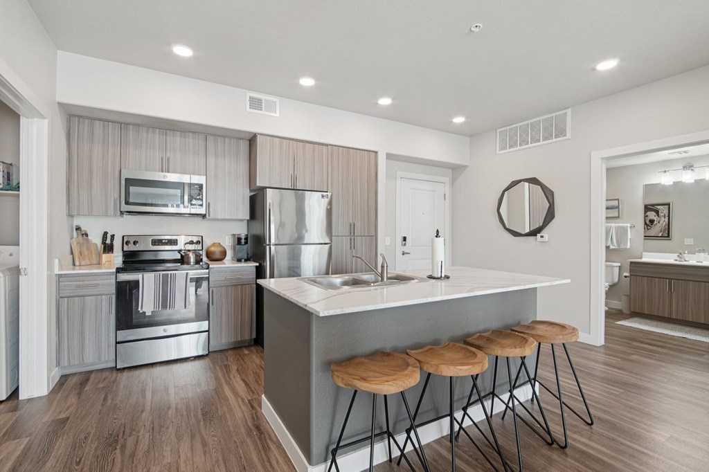 A modern kitchen with a large island and stools.