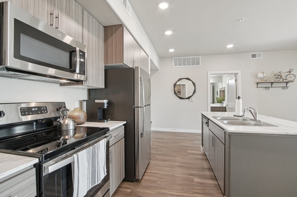 A modern kitchen with a stainless steel refrigerator and a black stove top.