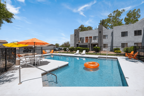 A pool with a sun lounger and umbrella.