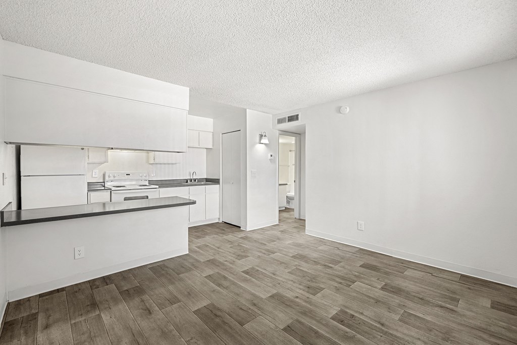 A kitchen with white cabinets and a wooden floor.
