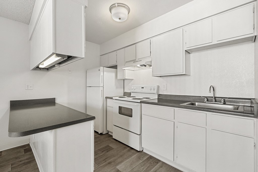 A white kitchen with a black counter top.