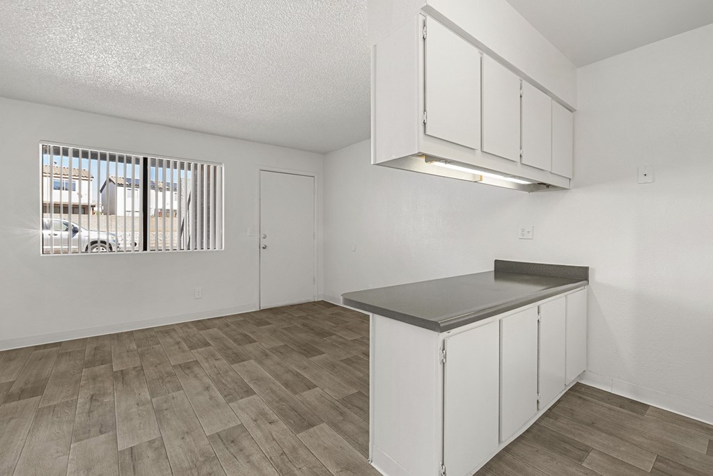 A kitchen with white cabinets and a wooden floor.