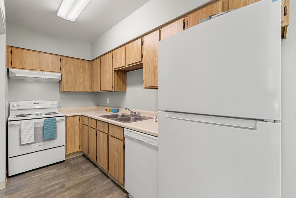 A kitchen with white appliances and wooden cabinets.