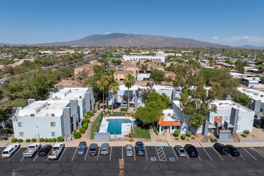 A parking lot with cars and a pool in the middle of a residential area.