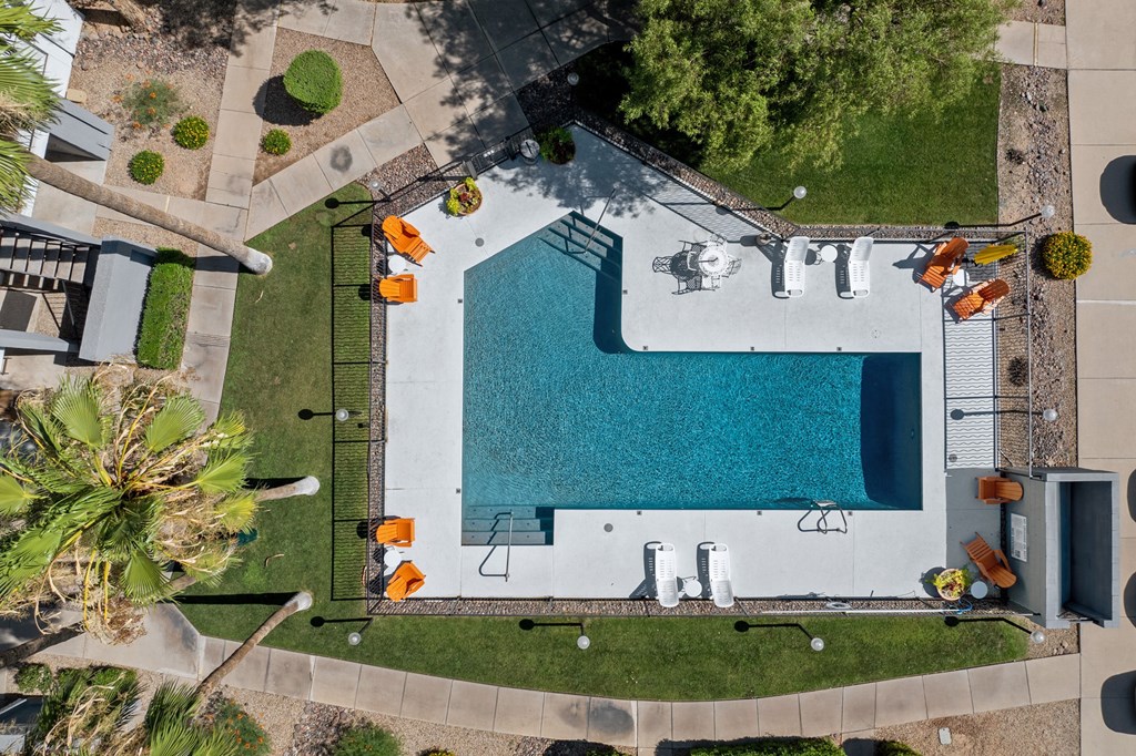 An aerial view of a pool surrounded by orange chairs and palm trees.