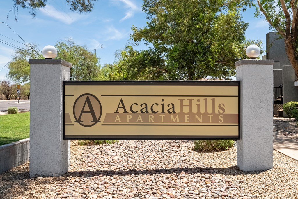 A sign for Acacia Hills Apartments stands in front of a tree.
