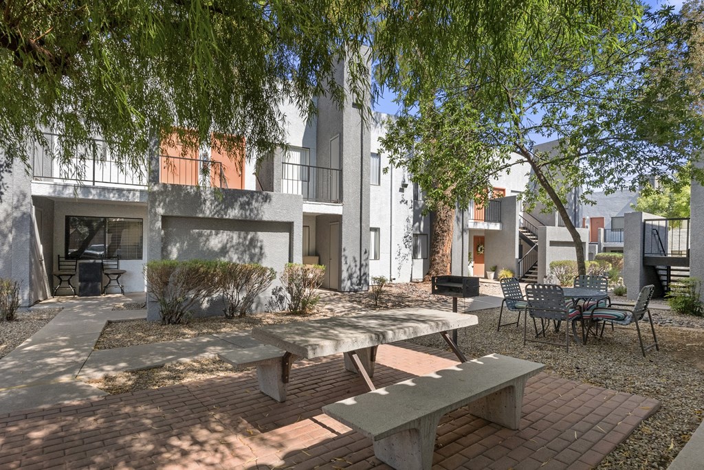 A patio with a table and chairs is surrounded by trees.