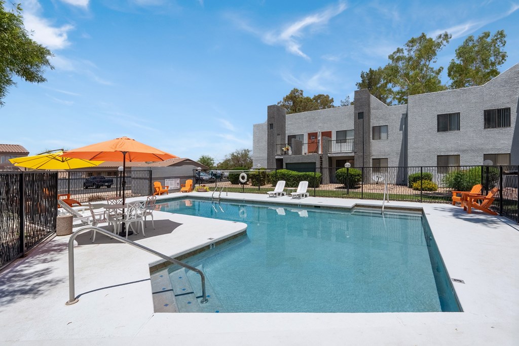 A swimming pool with a yellow umbrella and lounge chairs.