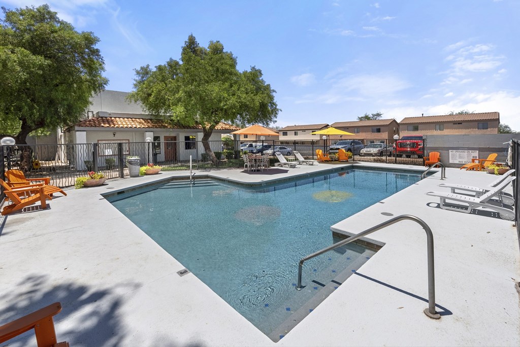 A swimming pool surrounded by a concrete patio and trees.