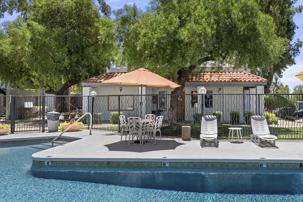A pool with a patio and chairs.