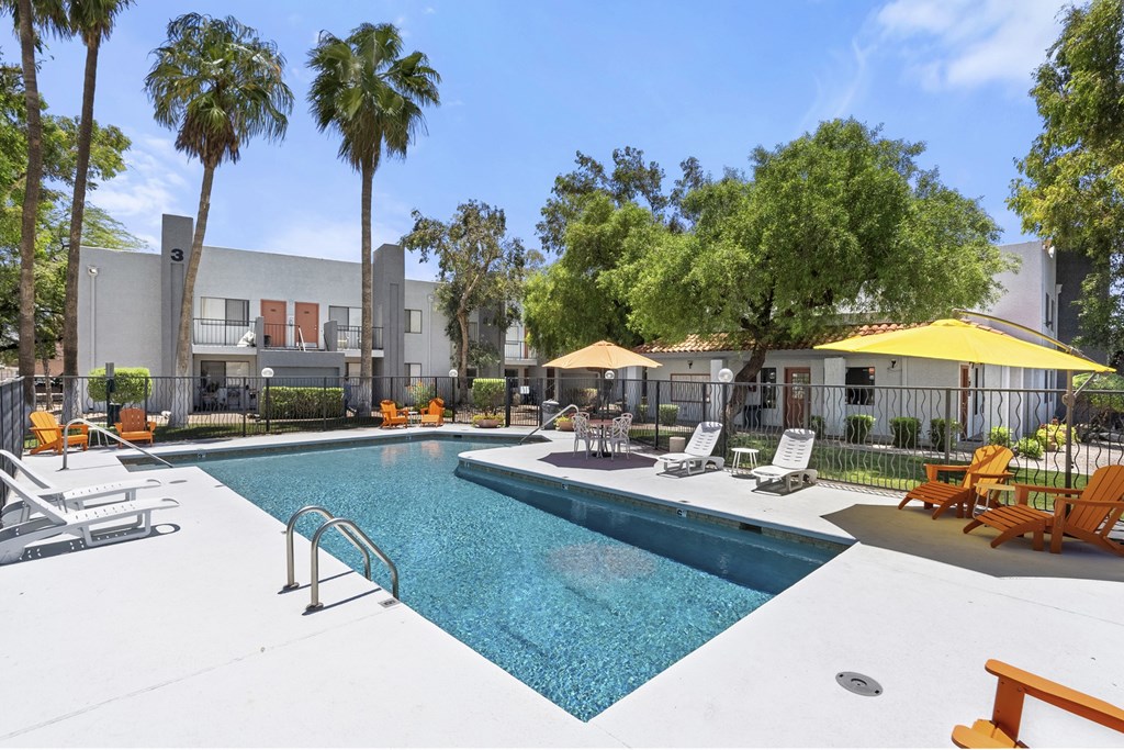 A swimming pool surrounded by palm trees and lounge chairs.