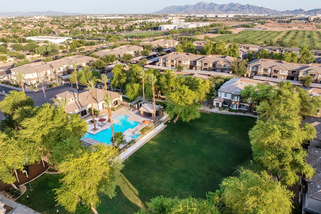 A bird's eye view of a neighborhood with a swimming pool and green lawns.