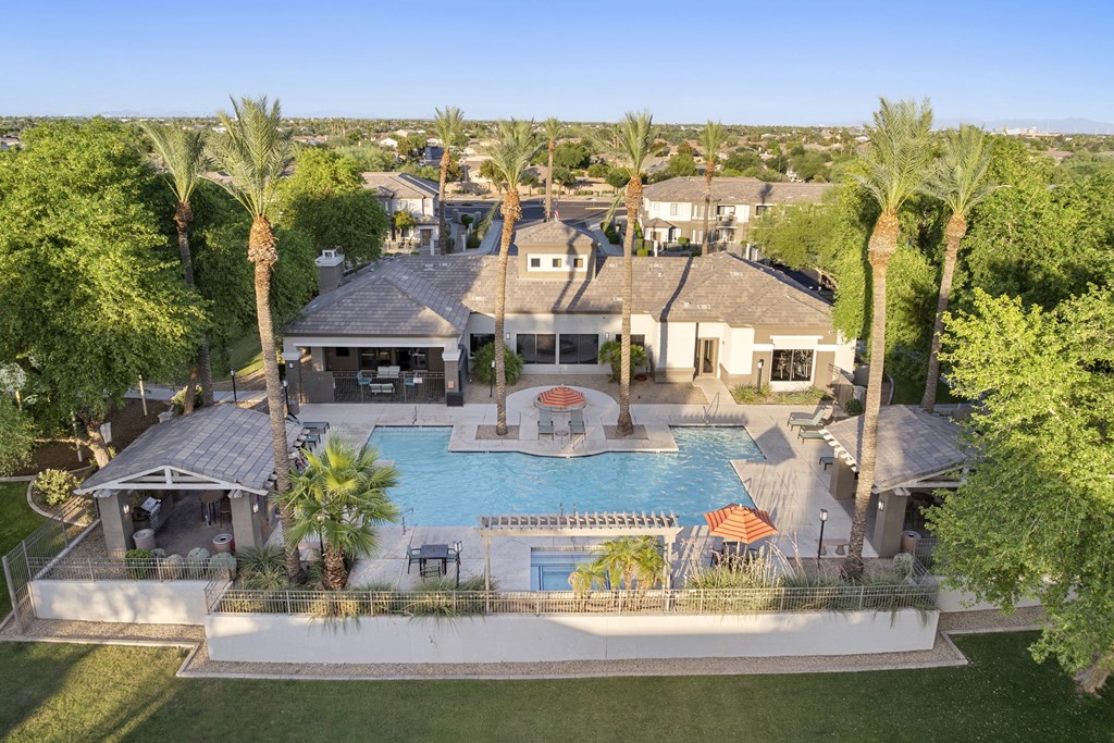 A large house with a pool surrounded by palm trees.