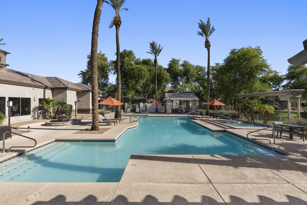 A large swimming pool surrounded by palm trees and lounge chairs.