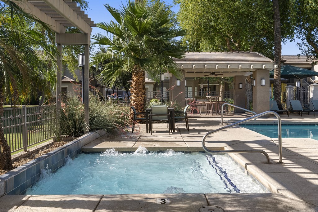 A pool with a waterfall and a hot tub in a backyard.