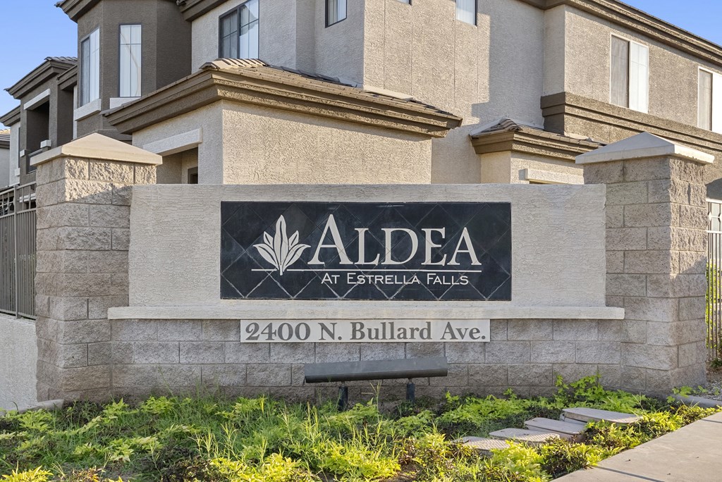 A sign for Aldea at Estrella Falls stands in front of a building.