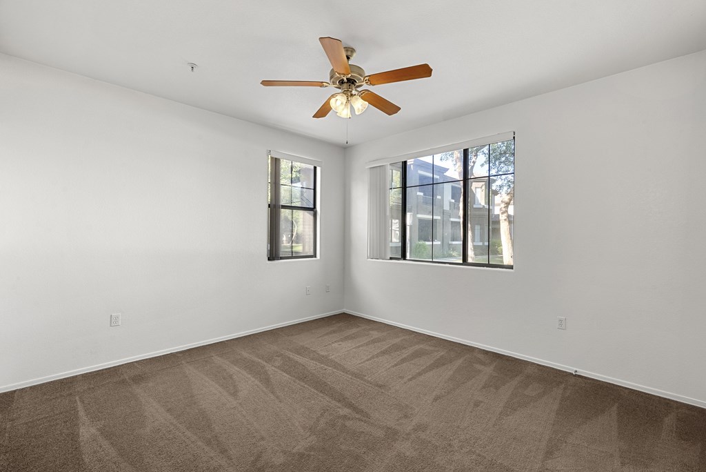 A room with a ceiling fan and carpeted floor.