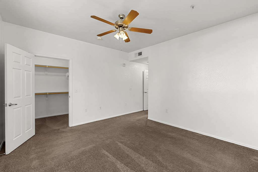A room with a ceiling fan and carpeted floor.
