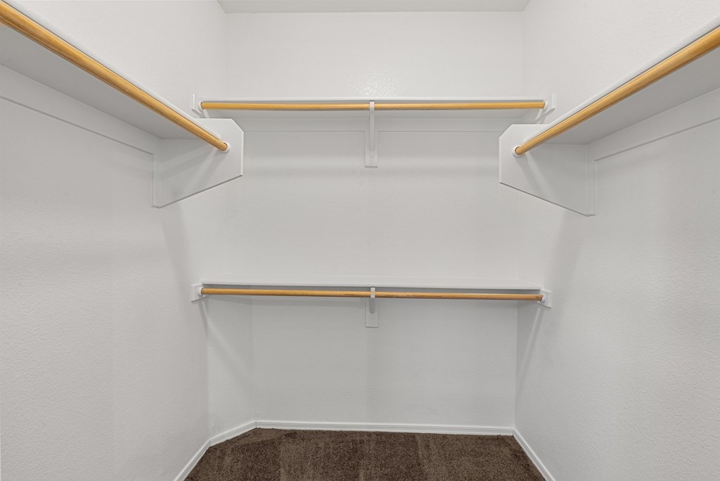 A white closet with two shelves and a carpeted floor.