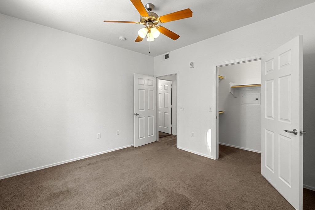 A room with a ceiling fan and carpeted floor.