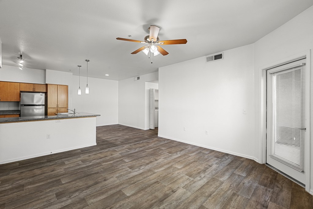 A room with a ceiling fan and wooden flooring.