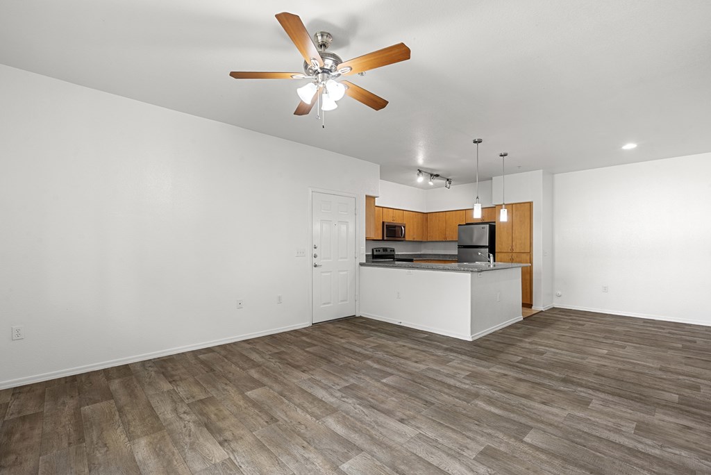 A room with a ceiling fan and a kitchenette.