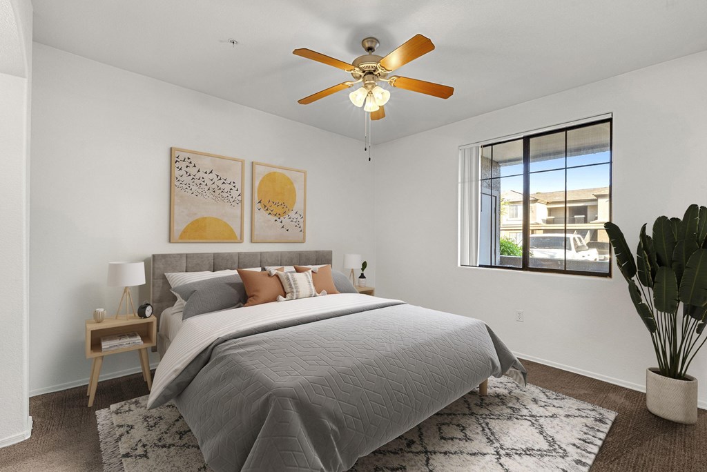 A bedroom with a bed, a ceiling fan, and a window.