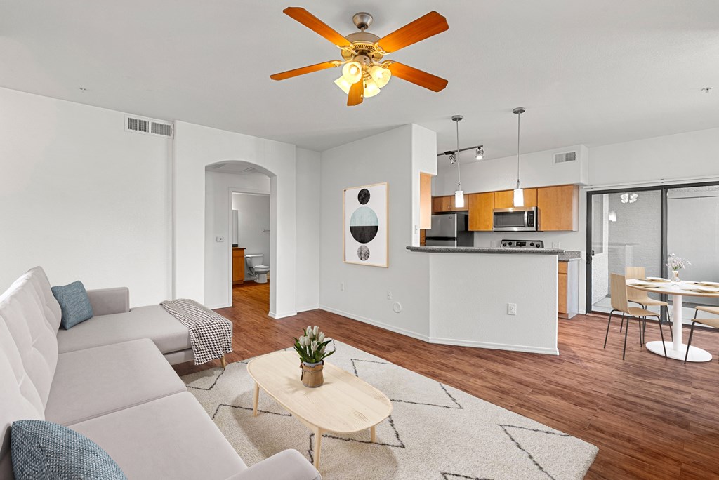 A living room with a grey couch and a ceiling fan.