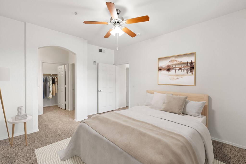 A bedroom with a bed, a ceiling fan, and a painting on the wall.