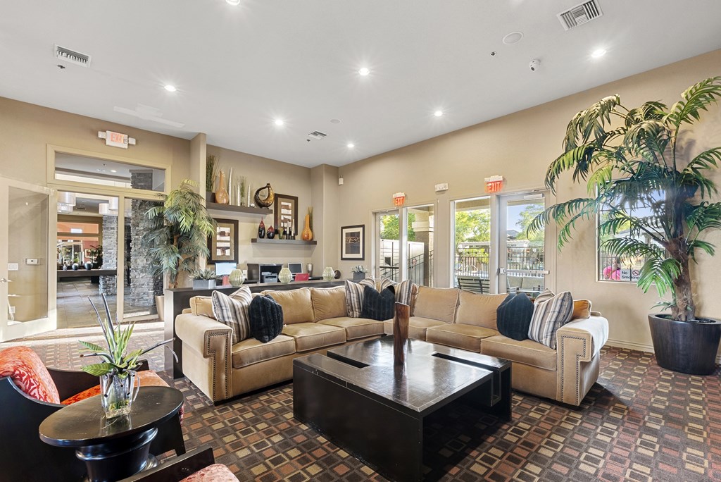 A living room with a couch, coffee table, and potted plants.