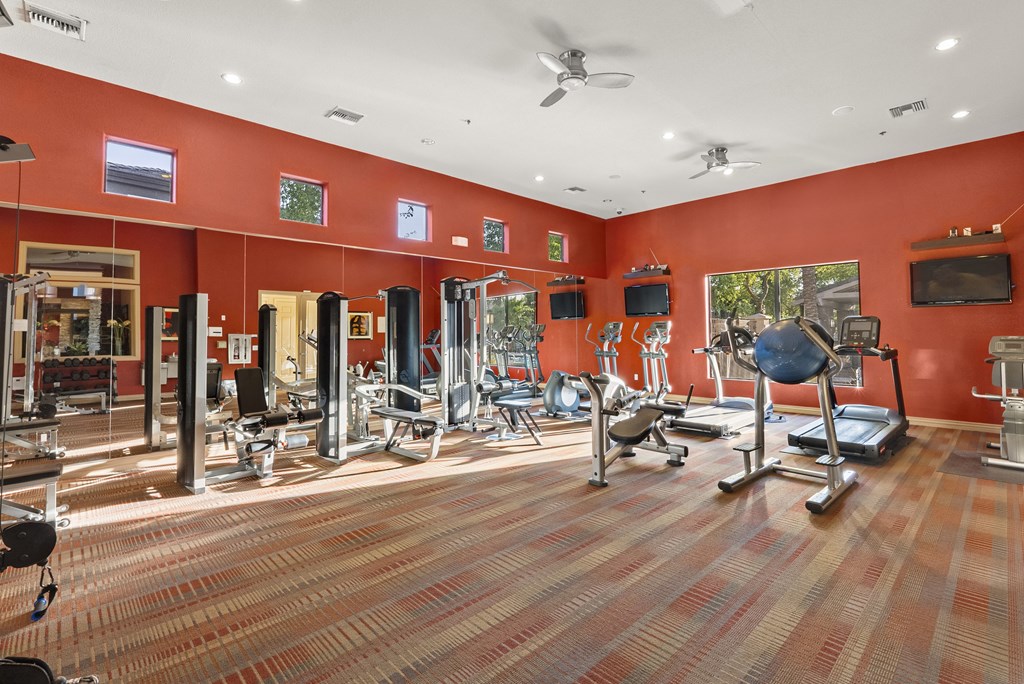 A gym with a variety of equipment including treadmills, weights, and exercise machines.