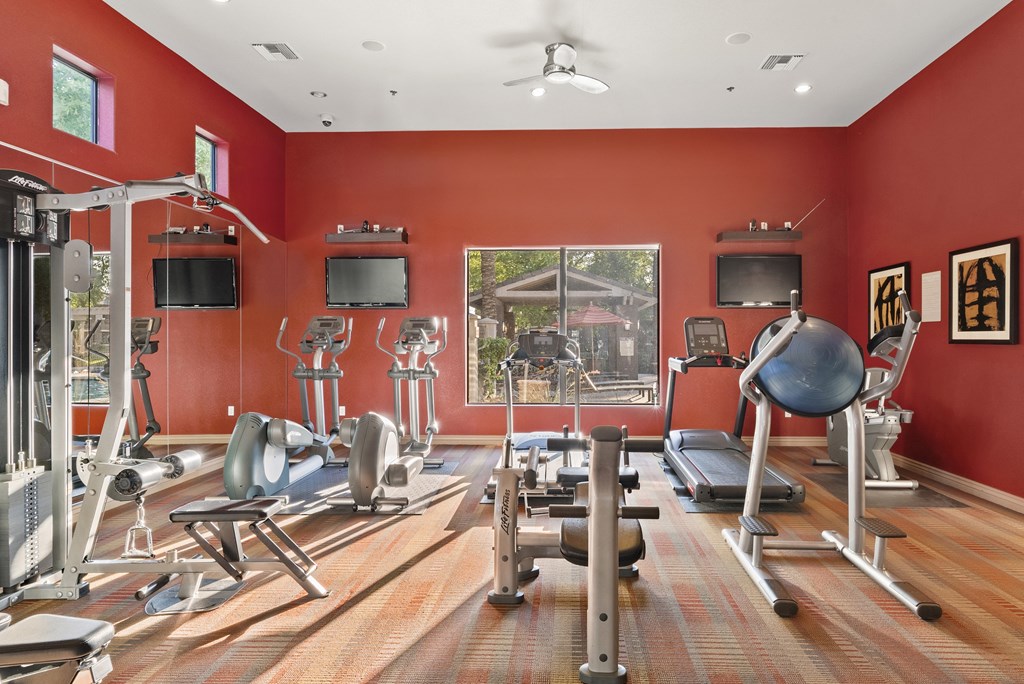 A gym with a variety of equipment including treadmills, weights, and exercise machines.