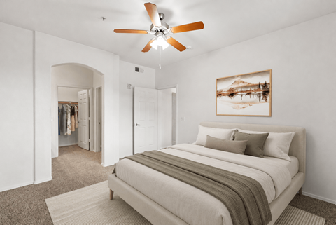 A bedroom with a large bed and a ceiling fan.