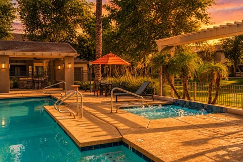 A pool with a slide and a patio area with a table and chairs.