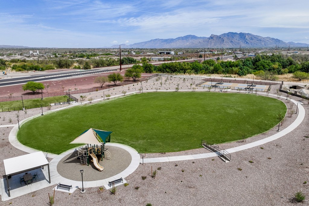 A playground with a green slide and a white canopy is surrounded by a circular path.