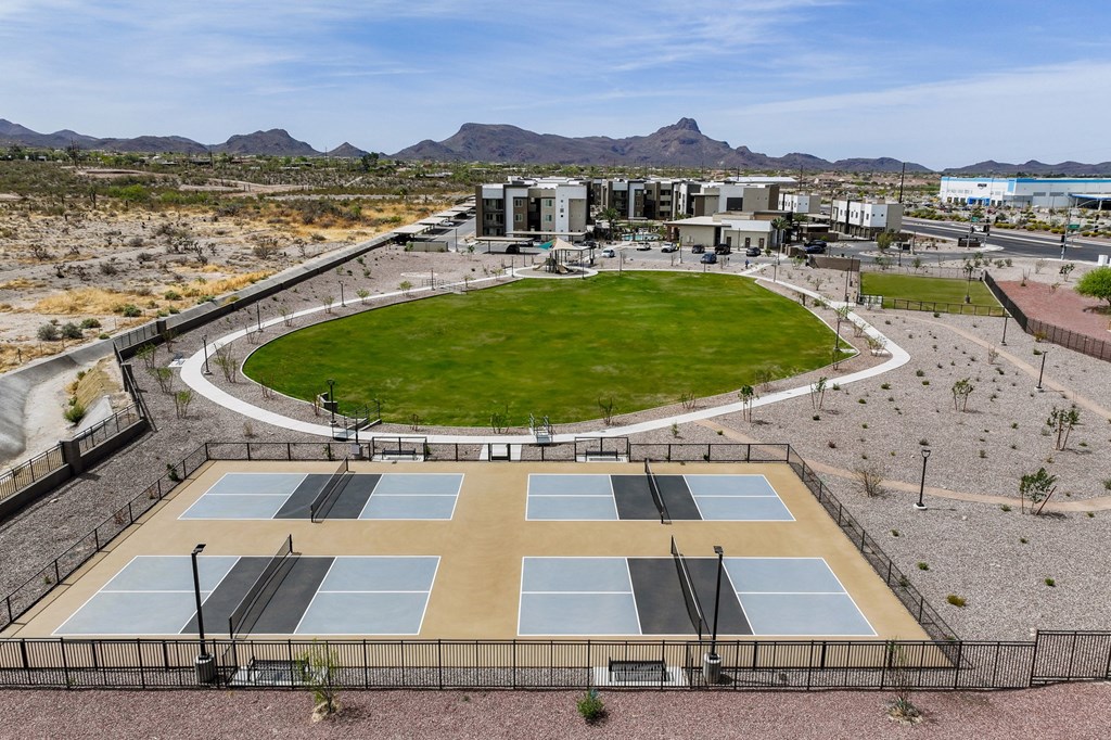 Tennis courts surrounded by a fence with a building in the background.