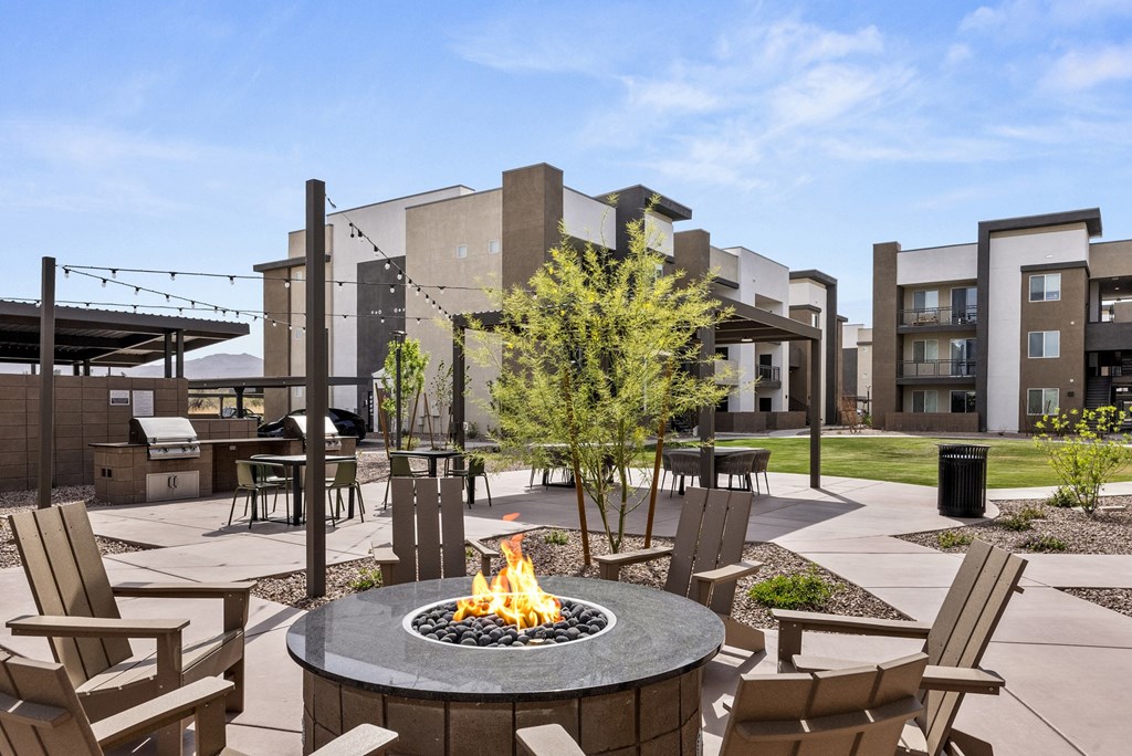 A fire pit sits in the middle of a patio surrounded by chairs.