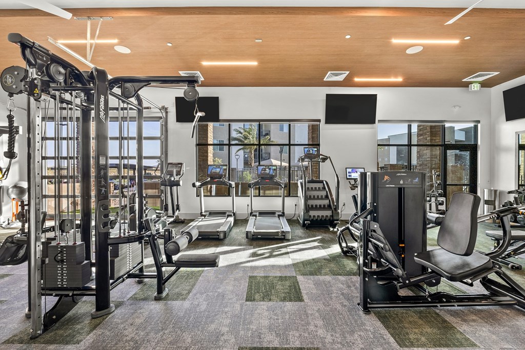 A gym with a variety of equipment including a treadmill, weights, and a bench press.