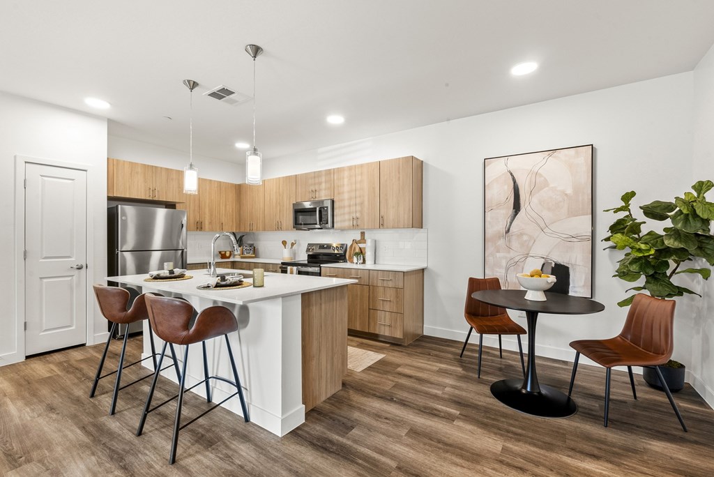 A modern kitchen with a white island and brown chairs.