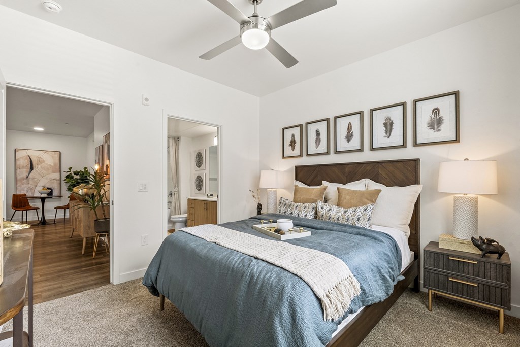 A bedroom with a bed, nightstand, and a ceiling fan.