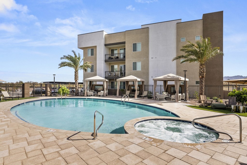A large swimming pool with a hot tub in front of a building.
