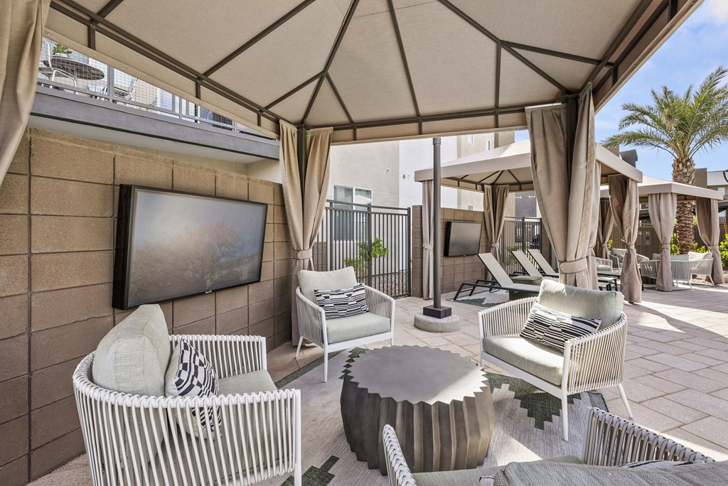 A patio with a white wicker chair and a round table.