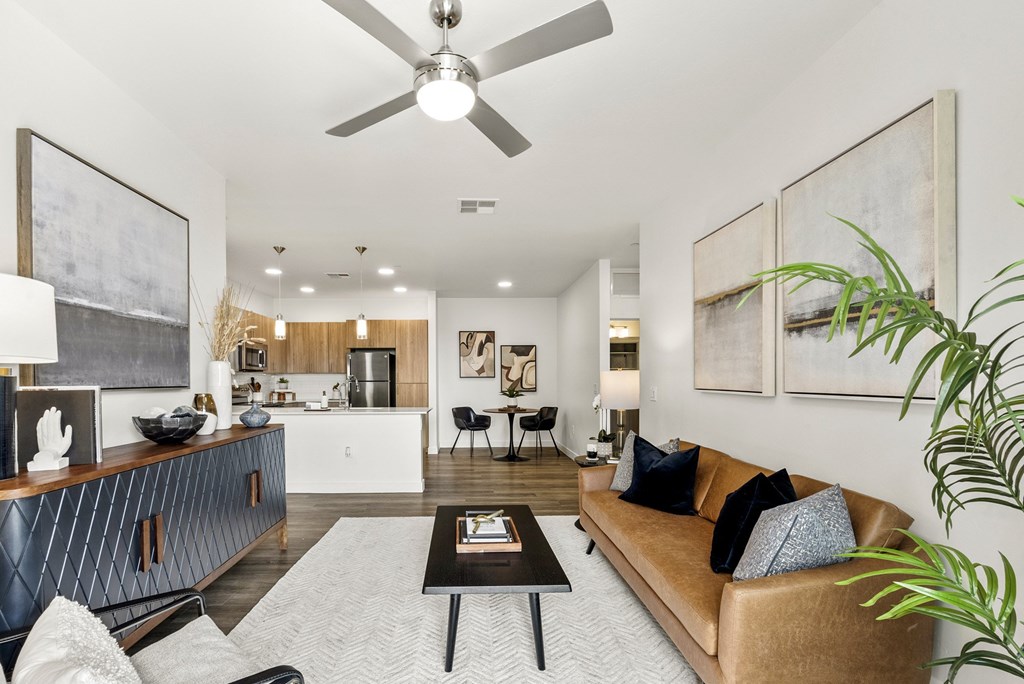 A living room with a brown couch and a ceiling fan.