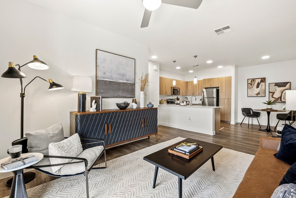 A modern living room with a kitchen in the background.