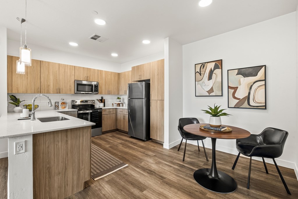 A modern kitchen with a wooden counter and black chairs.